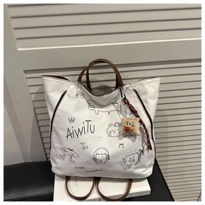 Détail d'un sac cabas en toile blanche avec gribouillages ludiques et anses en cuir marron