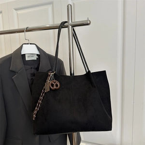 Minimalist black matte tote bag with pretzel pendant on silver hanger with grey suit
