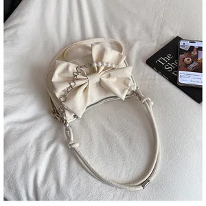Dettaglio della borsa bianco crema con grande fiocco in pelle, perle e petali in metallo