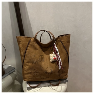 Vue détaillée du sac cabas en daim marron avec graffitis artistiques et logo