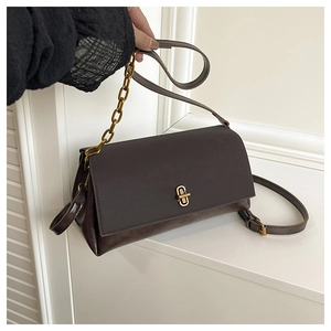 Détail du sac en cuir marron foncé avec fermoir rotatif doré et bandoulière en chaîne