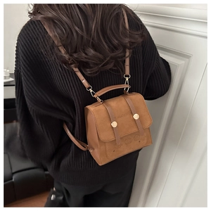 Rear view of a brown vintage-style mini backpack with textured matte finish on a model