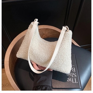 Close-up detail of plush white hobo bag with smooth faux leather strap on wooden chair