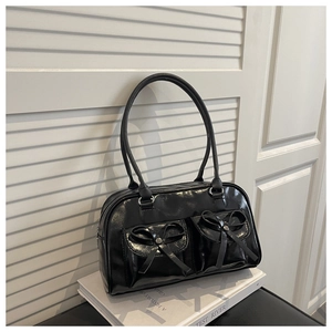 Detail of black glossy bowling bag with decorative bows and twin pockets on book