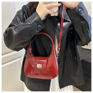 Close-up of red patent leather hobo bag with gold twist lock and glossy mirror finish