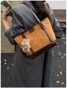 Outdoor lifestyle view of a vintage faux suede tote bag with cat pattern and plush charm