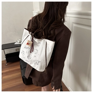 Détail du sac fourre-tout en toile blanche avec graffiti et breloque petit bonhomme