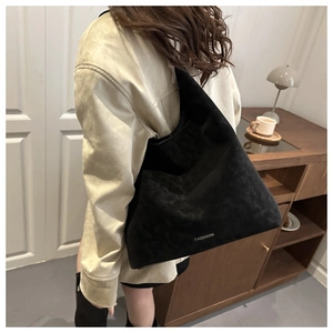 Dettaglio della borsa tote in pelle scamosciata nera con logo FASHION su una modella