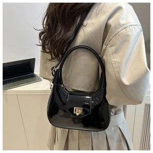 Detail of glossy black patent leather hobo bag featuring a vintage gold square buckle
