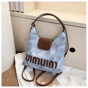 Nahaufnahme einer blauen Denim-Tasche mit braunem Lederbesatz und Metallreißverschluss