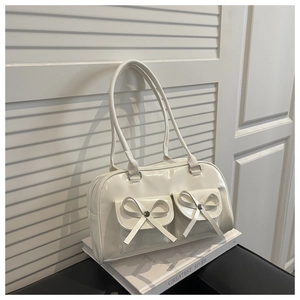 Detail of white glossy bow handbag with front magnetic pockets and silver rivet accents