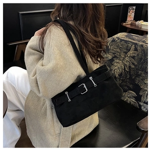 Détail d'un sac porté épaule noir mat avec boucle argentée porté avec un manteau beige