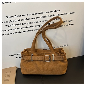 Détail d'un sac bandoulière vintage en daim marron avec boucle argentée décorative