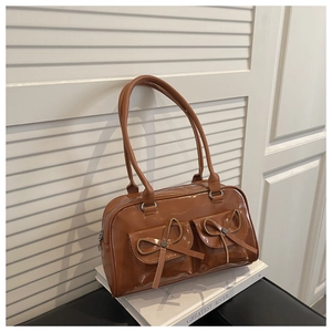 Close-up of caramel vintage leather shoulder bag with bow knots and dual pockets