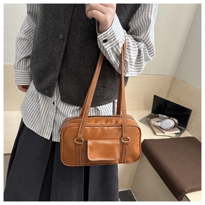 Close-up of brown faux leather square bag with silver metal ring and front pocket detail