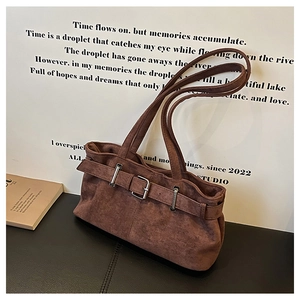 Détail du sac à épaule en cuir mat marron foncé avec sangle décorative et boucle en métal