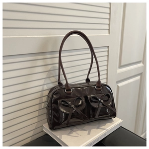 Detail of coffee brown patent leather shoulder bag with bows on front pockets