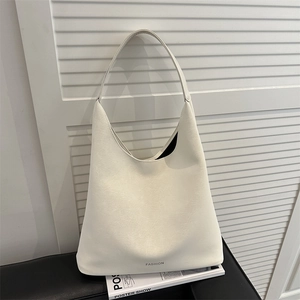 Sac fourre-tout beige minimaliste avec texte Fashion posé sur un banc en cuir noir