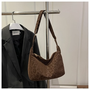 Detail of leopard print tote bag hanging next to a black blazer for size comparison