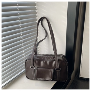 Detail of a dark brown square handbag with white contrast stitching and shiny finish