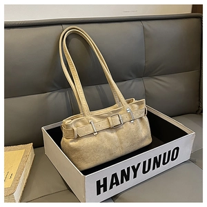 Détail du sac à épaule en toile beige avec boucle décorative dans un décor minimaliste