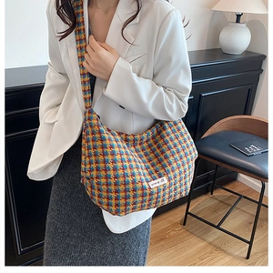 Detailed view of colorful houndstooth plaid weave and 'power off' patch on the crossbody bag