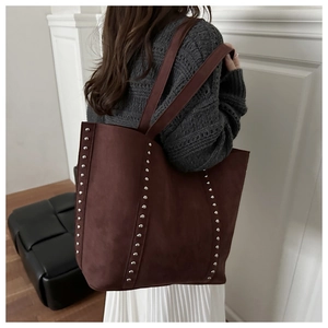 Détail du sac cabas en daim bordeaux avec rivets argentés et bandoulière de transport