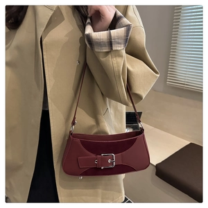 Close-up of burgundy underarm bag featuring leather patchwork and silver buckle detail