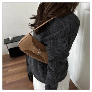 Detail of khaki patchwork underarm bag showing smooth leather and suede texture on model