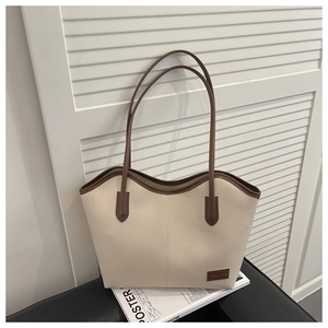 Detailed view of cream-white pebble leather tote bag with brown trim on a fashion magazine