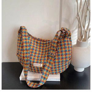 Close-up of colorful plaid tweed bag featuring adjustable strap and power off label