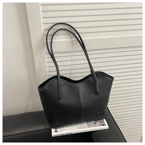 Detail of black pebbled leather tote bag with wavy top edge and stylish long shoulder strap