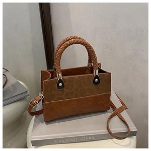 Detail of a brown leather crossbody bag with leopard print panel and woven handle