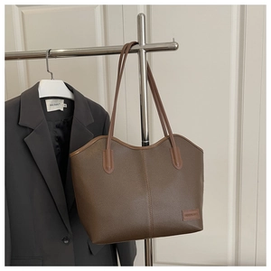 Detail of dark brown tote bag showing lychee grain texture and minimalist leather logo label