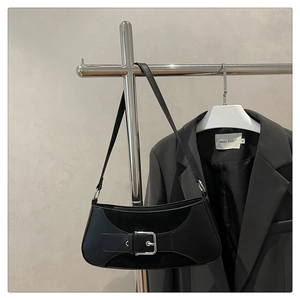 Detail of minimalist black baguette bag with silver buckle and leather suede texture