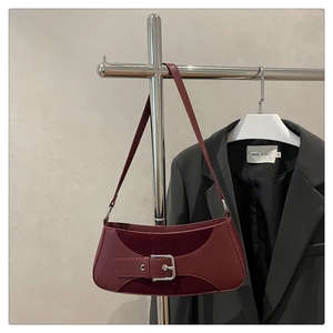 Detail view of burgundy leather baguette bag with silver buckle and mixed material texture
