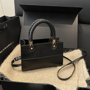 Retro black leather crossbody bag with woven handle and adjustable strap on plush fabric