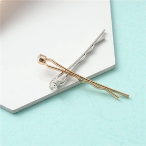 Détail des barrettes à cheveux dorées et argentées avec strass ronds sur fond bleu clair