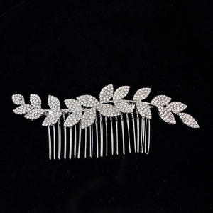 Close-up of silver bridal leaf hair comb with sparkling white rhinestones on black background