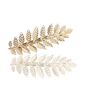 Barrette à cheveux élégante en feuille dorée polie sur un fond blanc neutre