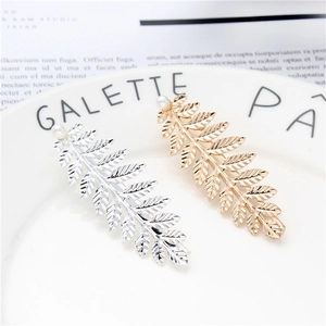 Detail of gold and silver leaf hair clips with white pearls on a white plate