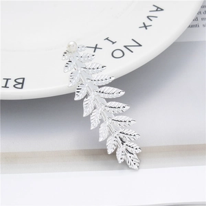 Detailed view of silver leaf hair clip with white pearl on a minimalist white ceramic plate
