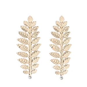 Paire de barrettes à cheveux en forme de feuille dorée avec strass sur fond blanc