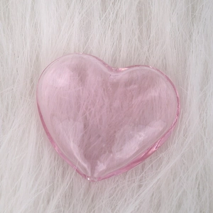 Pink heart-shaped glass perfume bottle pendant on soft white faux fur background