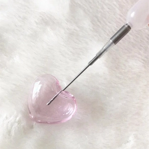 Pink heart-shaped glass bead for DIY jewelry making on white faux fur background