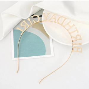 Detailed close-up of golden metal Birthday Girl headband with star motifs and silk background