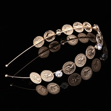Close-up of golden coin headband with embossed portraits and sparkling rhinestones
