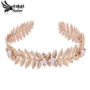 Detailed view of leaf-shaped gold bridal tiara with clustered white pearls on white background
