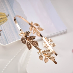 Elegant gold leaf headband with pearls on white ceramic plate, perfect for wedding accessories