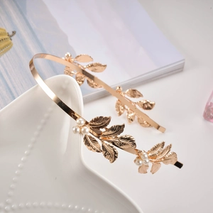 Golden bridal headband with metallic leaf details and elegant pearls on white ceramic tray